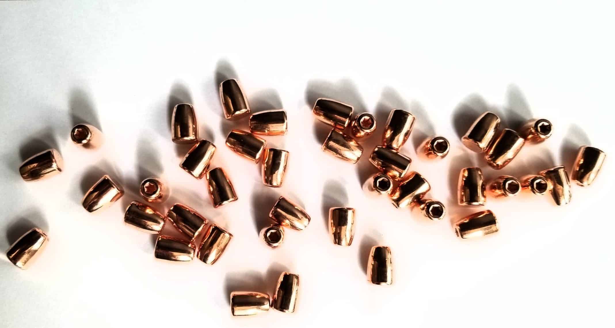 Copper-plated bullets scattered on white.